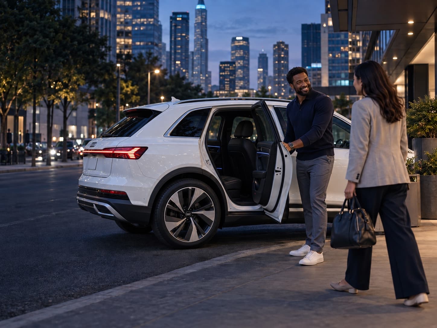 Professional driver welcoming a customer beside a white Audi e-tron at an evening city curb